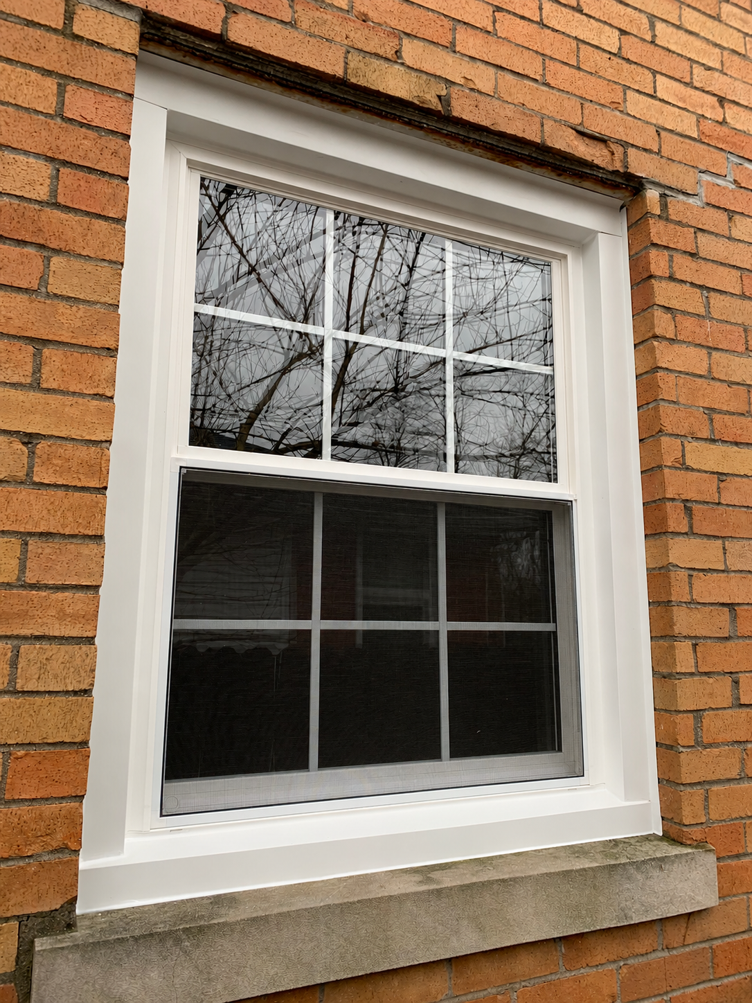 White vinyl double-hung replacement window with upper sash grids installed by WindowPROHVAC